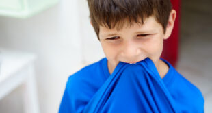 Close-Up Of Boy Biting Blue T-Shirt While Standing At Home